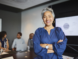 Smiling employee with arms folded standing in conference room