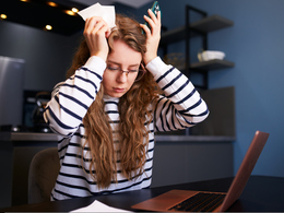 Stressed woman sitting in front of laptop and paperwork