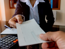 One person handing a blank check to another person