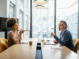 Two employees sitting across a large conference room table