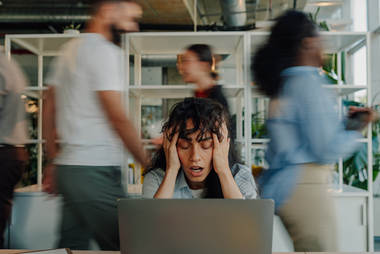 Woman stressed at work sitting in front of laptop holding head in hands