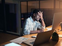 Employee sitting frustrated in front of computer hand on head