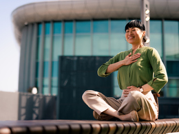 Person sitting outside office building meditating