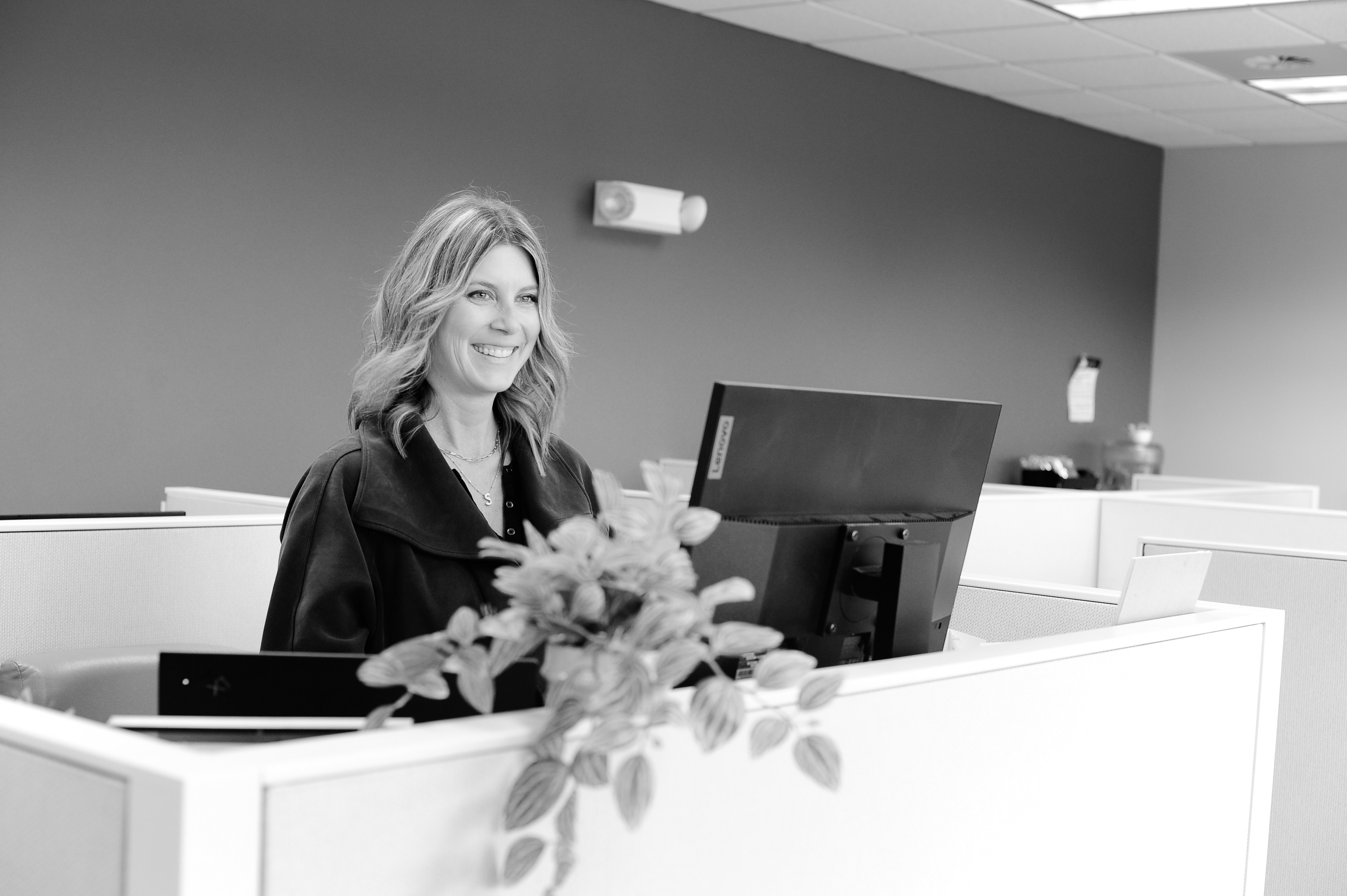 HR Services admin sitting at a desk and smiling at her computer.