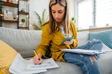 Woman filling out paperwork on couch